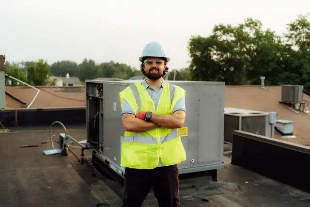 Prime technician beside a rooftop HVAC unit