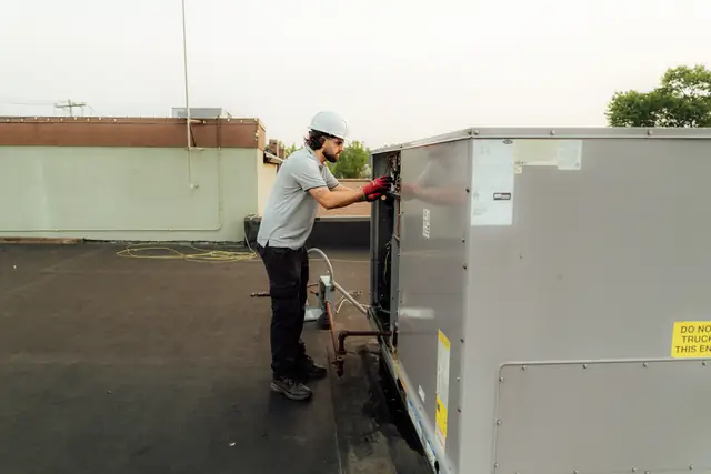 Technician opening a rooftop unit's access panel for service