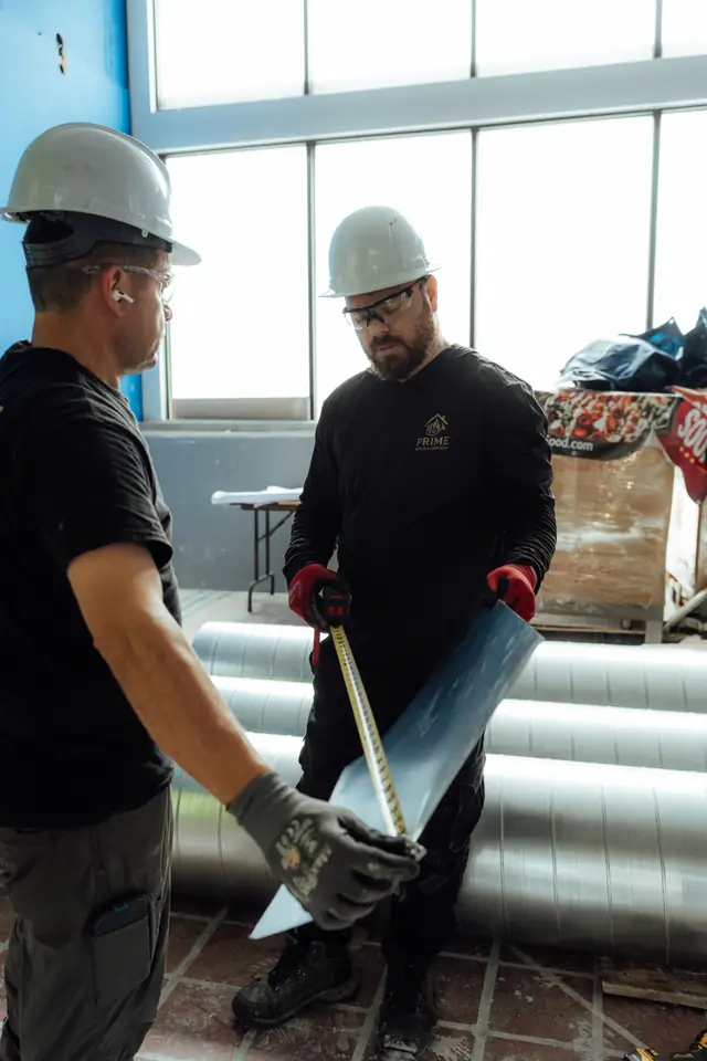 Technicians fitting ductwork near a window