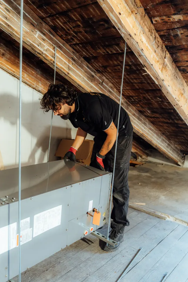 Prime technician adjusting an air handler during an attic installation