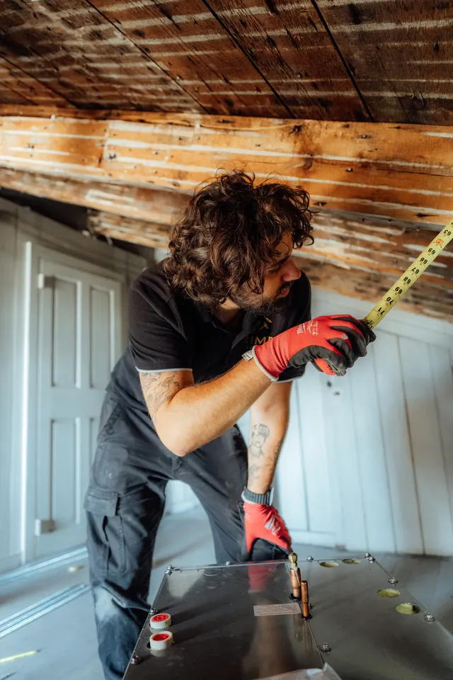 Prime technician measuring copper line connections on a new unit