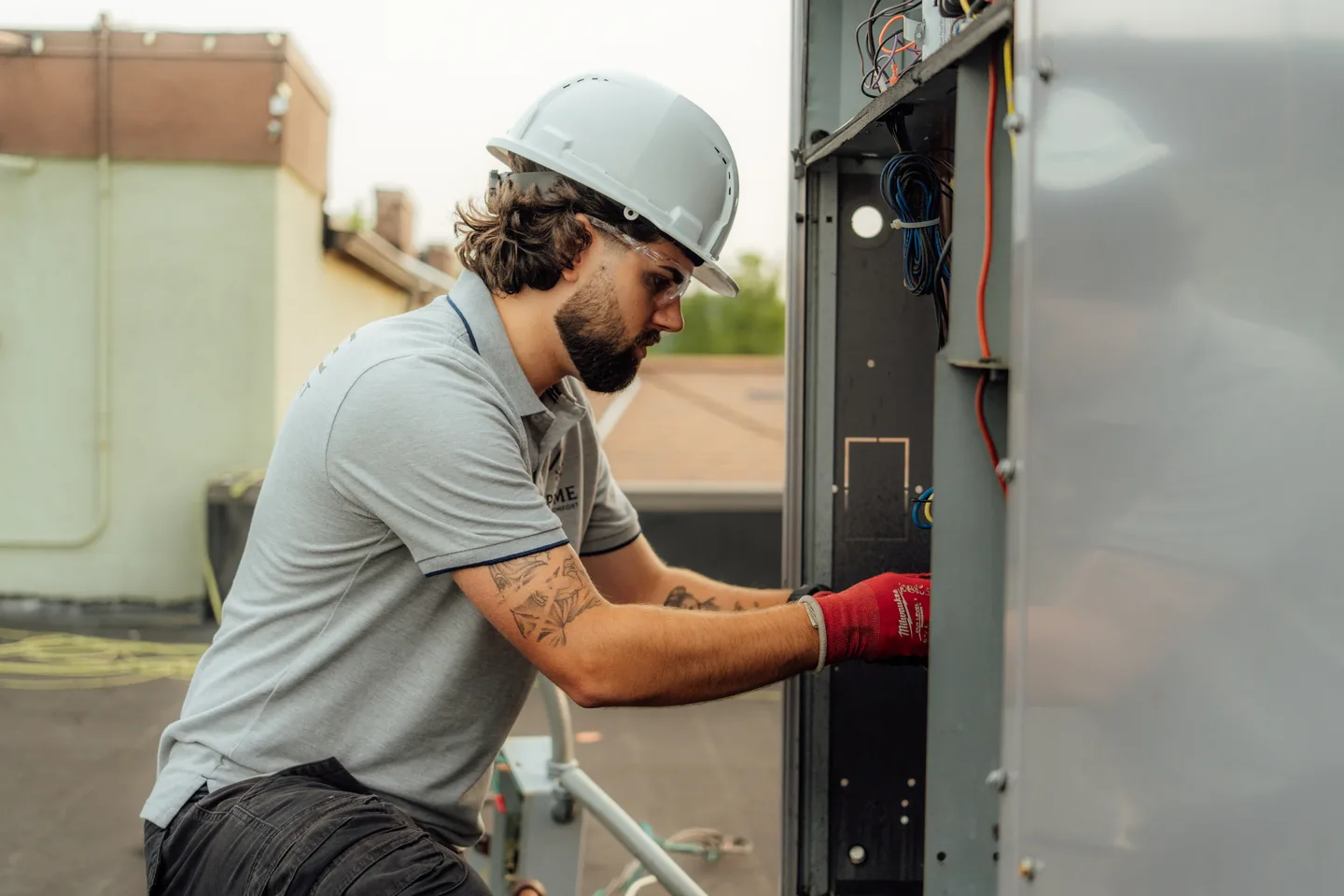 Prime technician opening a rooftop HVAC unit's electrical panel for diagnostics
