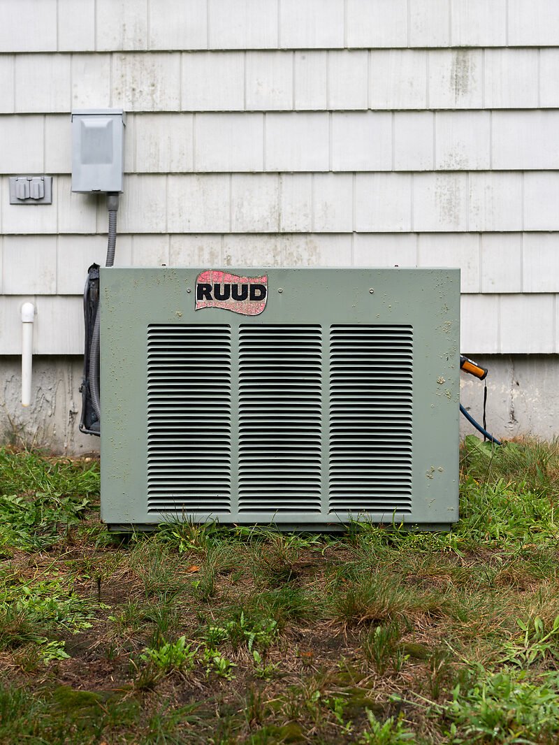 A weathered, corroded outdoor heat pump unit before replacement at a South Shore home