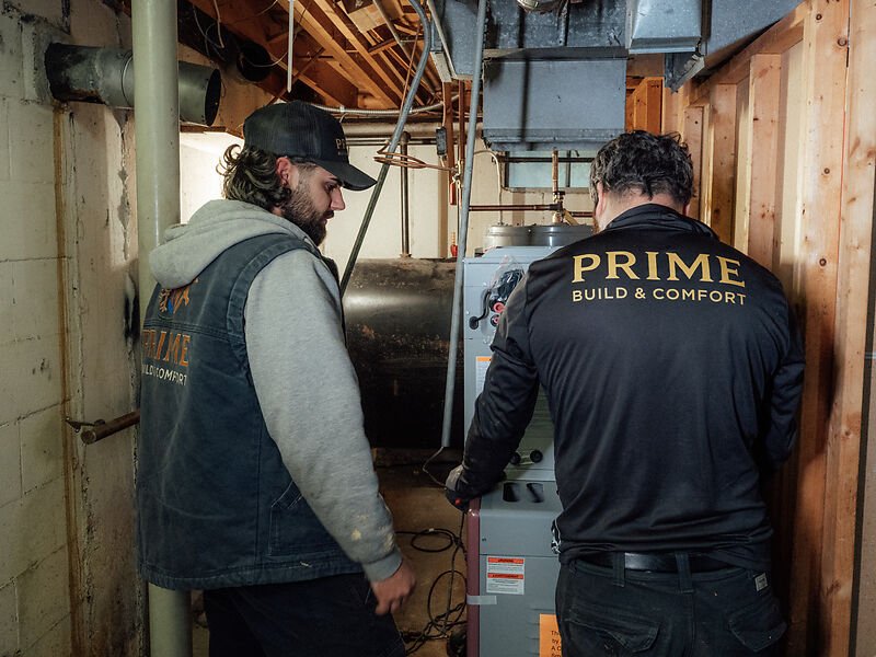 Two Prime technicians working on an old oil furnace before it comes out
