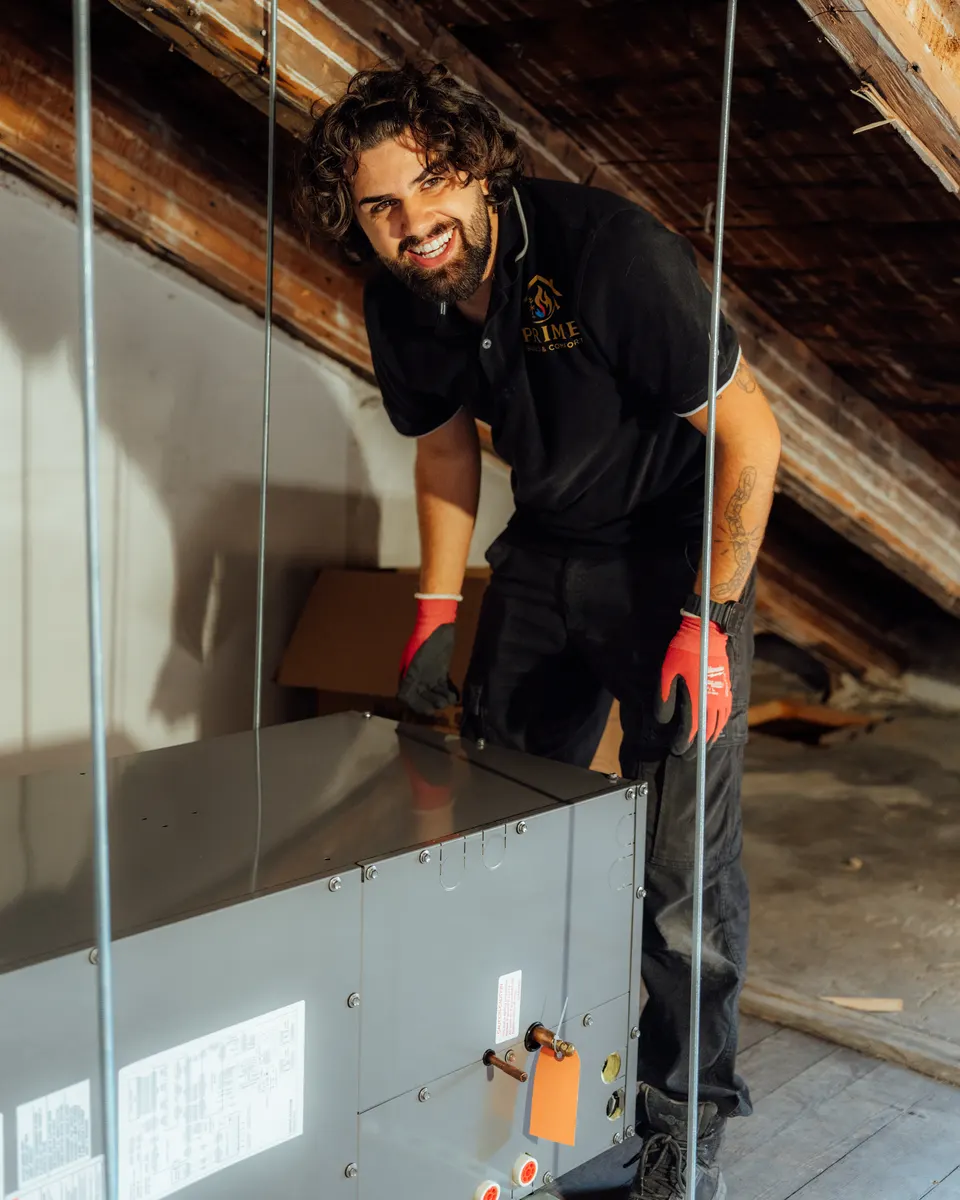 A Prime technician servicing a furnace in an attic