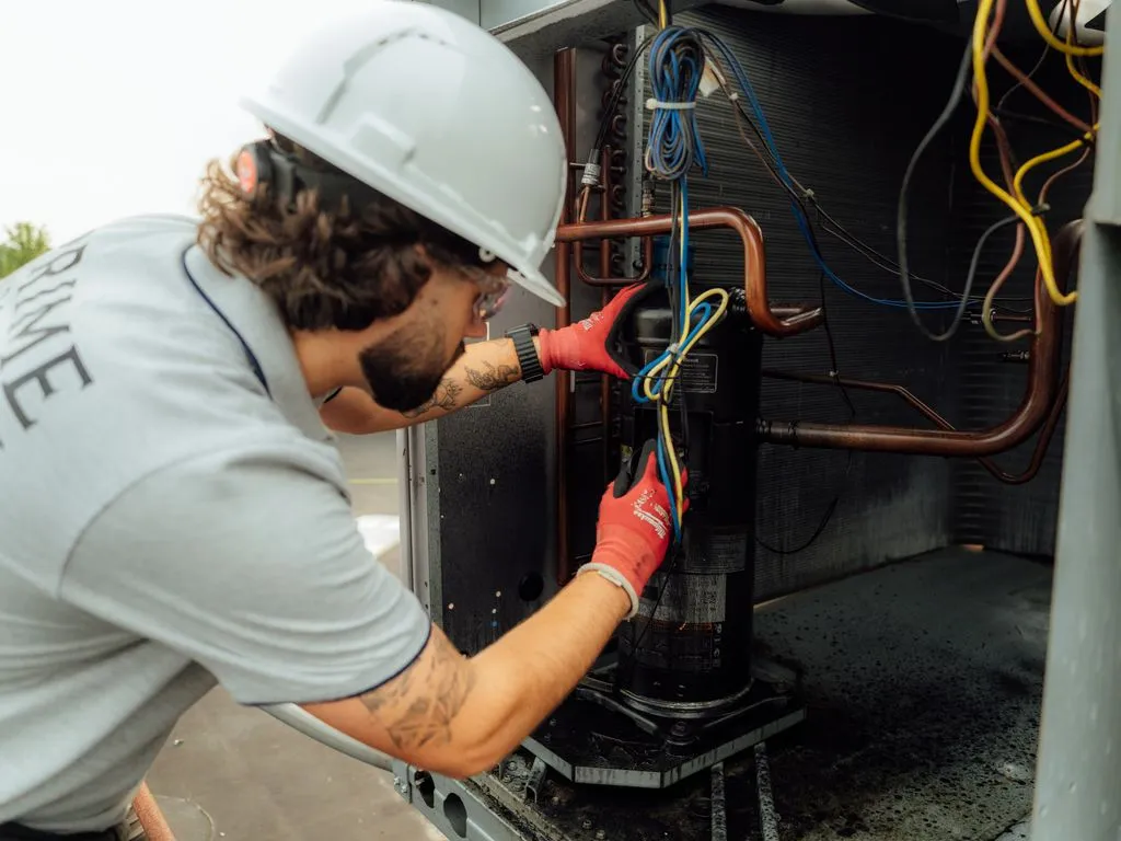 Prime technician servicing an HVAC unit and copper line set